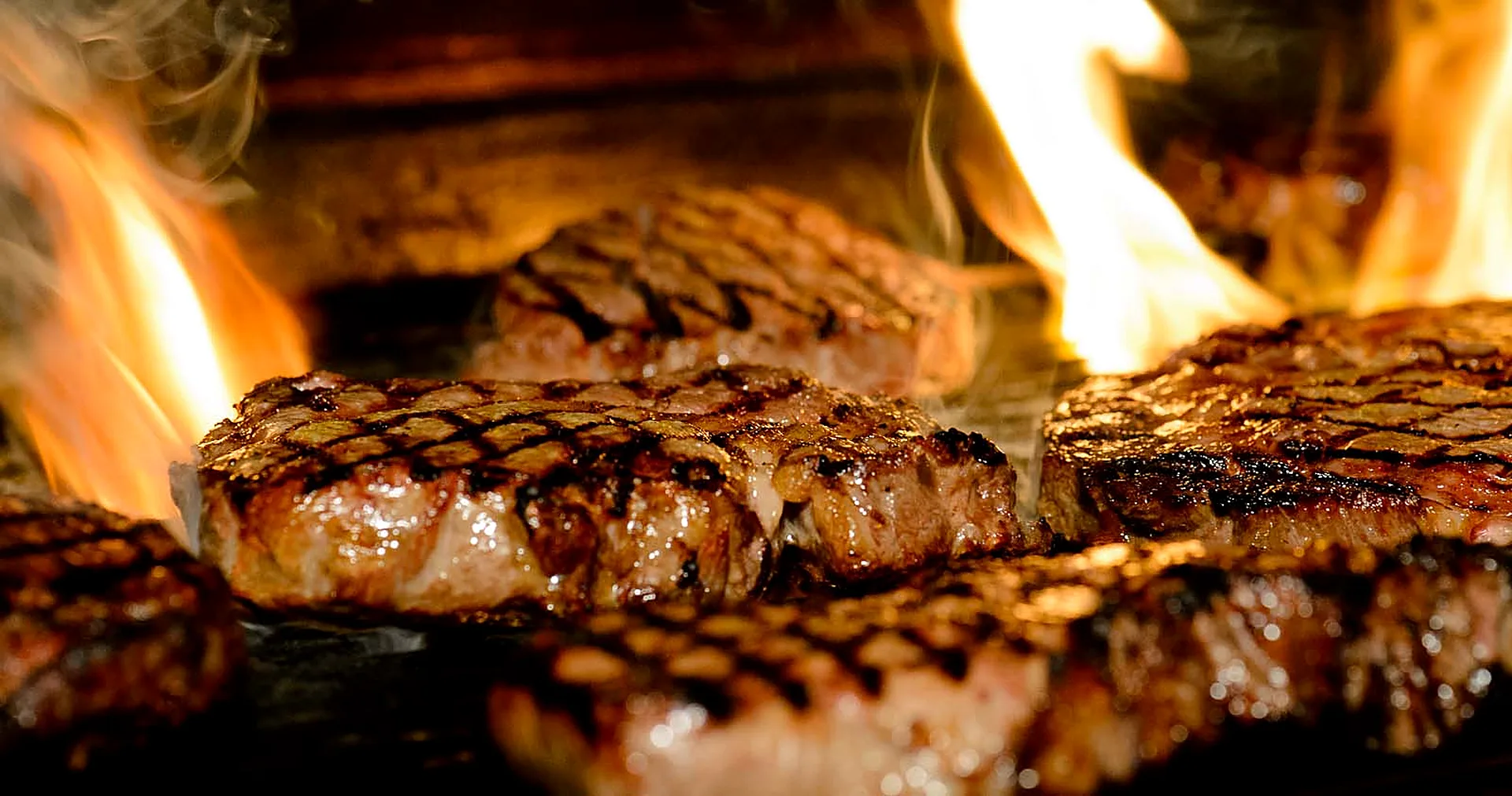 Steaks over open charcoal flame at Charcoal Grill on the Hill